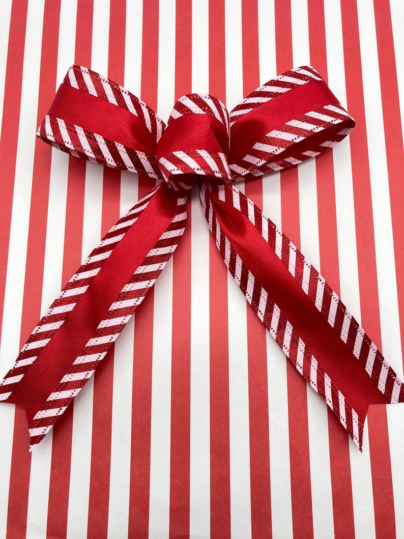 May include: A red and white striped ribbon bow tied on red and white striped wrapping paper.