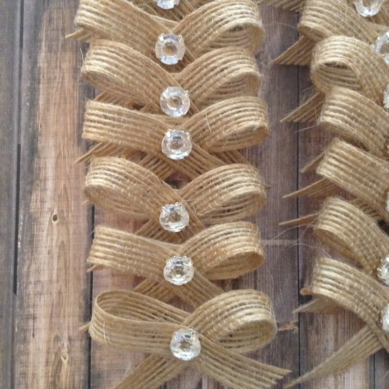 May include: A set of burlap bows with clear rhinestone embellishments. The bows are tied in a criss-cross pattern and are perfect for adding a rustic touch to any project.
