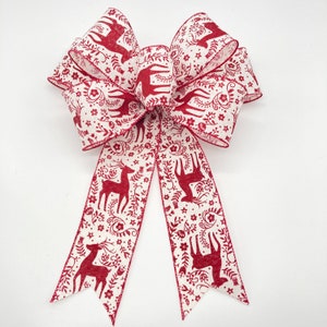 May include: A red and white Christmas bow with a reindeer and floral pattern. The bow is tied with a long tail.