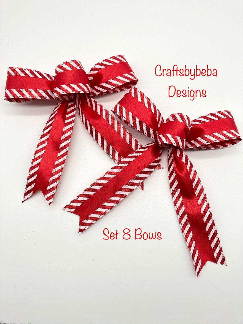 May include: A set of eight red and white striped bows with a glittery finish. The bows are tied with a satin ribbon and are perfect for adding a festive touch to any occasion.  "Craftsbybeba Designs" is written in the top right corner of the image.  "Set 8 Bows" is written in the bottom centre of the image.