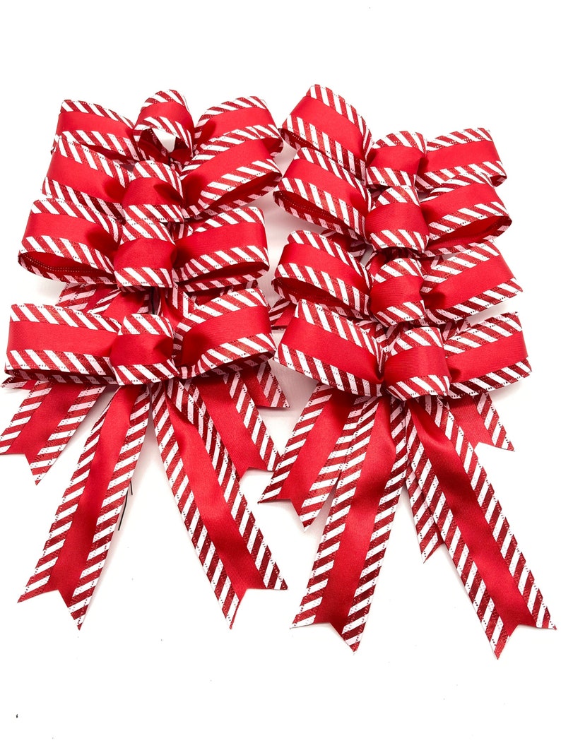 May include: A set of six red and white striped bows with a glittery finish. The bows are tied with a loop and tails.