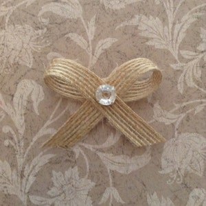 May include: A brown burlap bow with a clear rhinestone in the center.