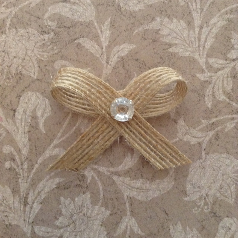 May include: A brown burlap bow with a clear rhinestone in the center.