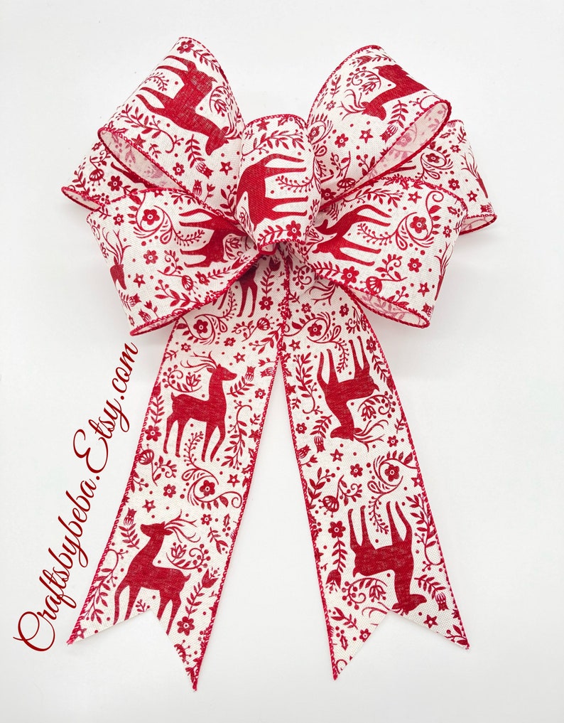 May include: A red and white Christmas bow with a reindeer and floral pattern. The bow is tied with a double loop and two tails.