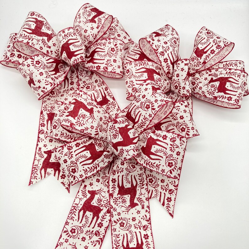 May include: Three red and white fabric bows with a reindeer pattern. The bows are tied with a loop and tail.