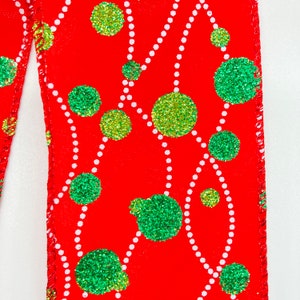 May include: Red ribbon with a white and green polka dot pattern. The dots are green with a glittery finish and are arranged in a random pattern on the ribbon.