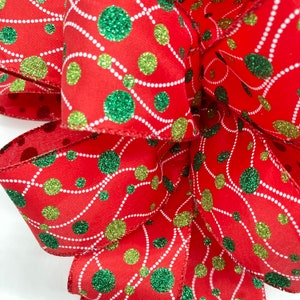 May include: Red ribbon with green and gold glitter polka dots and white lines. The ribbon is folded into a bow shape.