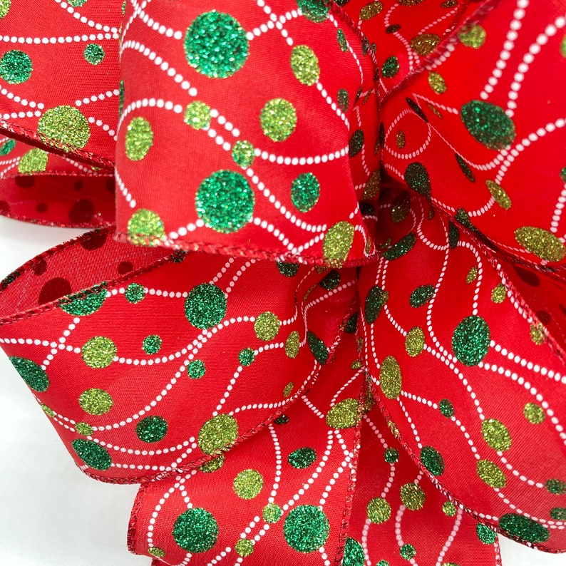 May include: Red ribbon with green and gold glitter polka dots and white lines. The ribbon is folded into a bow shape.