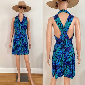 May include: A sleeveless blue and green floral print dress with a criss-cross back detail. The dress has a collared neckline and a fitted bodice.