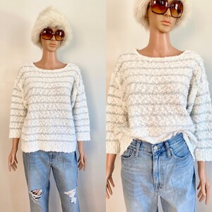 May include: White sweater with grey stripes and a textured knit. The sweater has a round neckline and 3/4 sleeves.