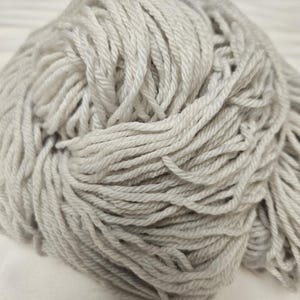 Peut inclure: Une pelote de laine gris clair, étroitement enroulée et texturée. La laine semble être une fibre naturelle et douce, adaptée aux projets de tricot ou de crochet. La couleur neutre la rend polyvalente pour diverses créations artisanales.