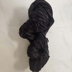 May include: A skein of dark gray yarn with subtle variations in tone. The yarn appears to be tightly spun, with a slightly textured surface. The overall color is a deep charcoal, suitable for knitting or crocheting projects.