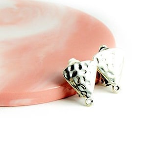 Könnte beinhalten: Ein Paar silberfarbene, strukturierte Ohrringe mit gehämmertem Metalldesign, die auf einer rosa-weißen Marmoroberfläche liegen. Die Ohrringe haben eine dreieckige Form und eine kleine Schlaufe unten. Der Hintergrund ist weiß.