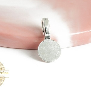 Puede incluir: Biela de colgante plateada con una superficie redonda, plana y en blanco. La anilla está diseñada para sujetar un cabujón redondo.