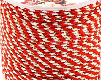 May include: A spool of red and gold jewellery cord. The cord is twisted and has a white stripe running through it. The spool is labelled "Jewellery cord" in black text.
