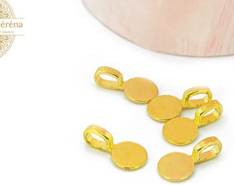 May include: Gold-coloured jewellery findings with a circular base and a loop for attaching to other components. The findings are displayed on a white surface with a blurred pink and white background. The logo "Les Apprêts de Séréna" is visible.