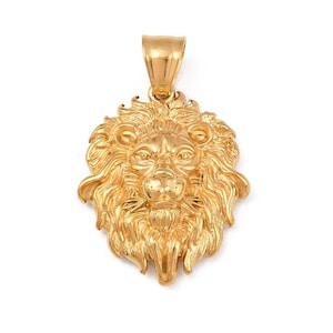 Puede incluir: Colgante de león dorado con una melena y una cara detalladas. El colgante tiene un lazo en la parte superior para una cadena. La cara del león está centrada, con intrincados detalles en el pelaje y los rasgos faciales.