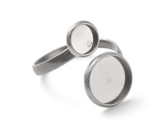 Puede incluir: Un anillo ajustable plateado con dos engastes redondos. Los engastes tienen un área empotrada para agregar un diseño. El anillo tiene un diseño simple y moderno.