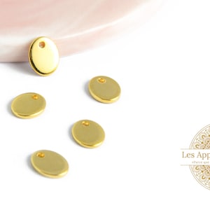 Peut inclure: Cinq cercles en métal de couleur dorée avec un petit trou au centre. Les cercles sont dispersés sur une surface blanche.