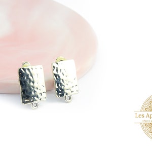 Può includere: Due basi rettangolari per orecchini in argento con una texture martellata. Le basi hanno un anello su ciascun lato per attaccare i fili degli orecchini.
