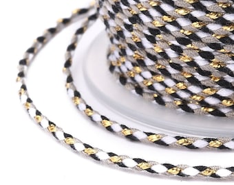 May include: A spool of braided cord with black, white, and gold threads. The cord is twisted and has a metallic sheen.