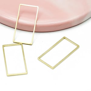 Könnte beinhalten: Drei dünne, goldfarbene rechteckige Metallrahmen. Jeder Rahmen ist in der Mitte offen und weist eine glatte, gleichmäßige Oberfläche auf. Die drei identischen geometrischen Formen sind in einer Gruppe angeordnet und zeigen ihr hohles Design.