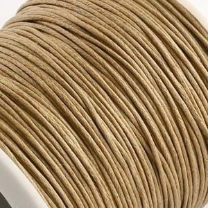 Puede incluir: Primer plano de una bobina de cordón de color beige. El cordón está enrollado apretadamente, revelando una superficie texturizada. El cordón parece estar hecho de una fibra natural, adecuado para varios proyectos de artesanía. La bobina es blanca.