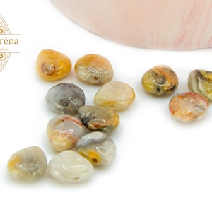 Peut inclure: Dix pierres en forme de cœur en agate, dans des tons de brun, blanc et orange. Les pierres sont lisses et polies, avec un aspect naturel et organique.