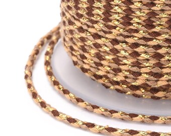 May include: A spool of brown and gold braided cord with a metallic sheen. The cord is wound around a white spool.