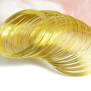 May include: A pile of 30 gold-coloured metal wire rings, stacked and overlapping. The rings are thin and delicate, and they are perfect for crafting jewellery or other projects.