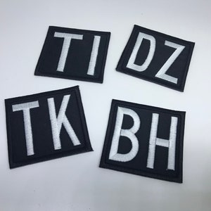 May include: Four black fabric patches with white embroidered letters. The patches spell out "T I D Z" and "T K B H".