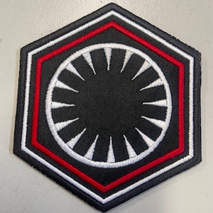 以下が含まれることがあります： スターウォーズのファーストオーダーのシンボルに似ている、白の円と放射状の線を持つ黒と赤の刺繍パッチ