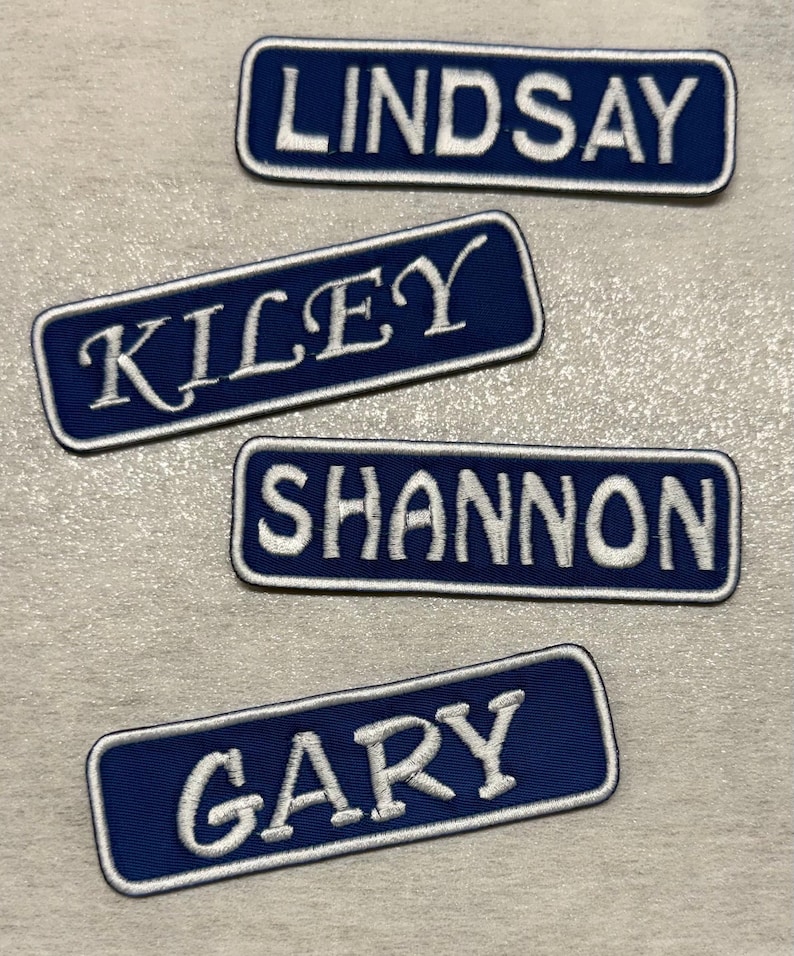 Pode incluir: Quatro patches bordados com nomes. Cada patch &eacute; um ret&acirc;ngulo azul marinho com uma borda branca e texto bordado branco. Os nomes s&atilde;o Lindsay, Kiley, Shannon e Gary. Ideais para roupas ou acess&oacute;rios.