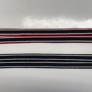 May include: Two pairs of black fabric trim with white and red stripes. The trim is approximately 1 inch wide.