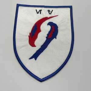 May include: A white embroidered patch with a blue and red stylized 'S' shape. The patch has a blue border and the text 'VTV' at the top.