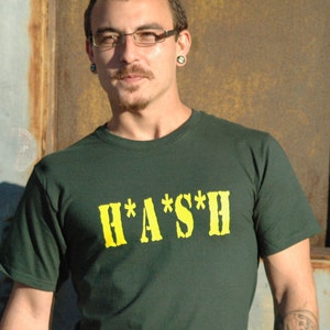 May include: A dark green t-shirt with a yellow graphic that says "H*A*S*H".