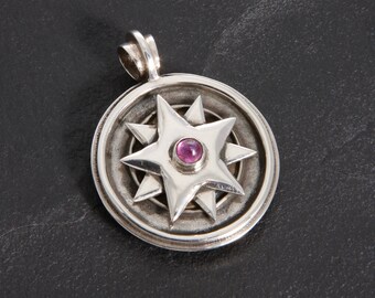 May include: A silver pendant featuring an eight-pointed star design with a pink gemstone at its centre.