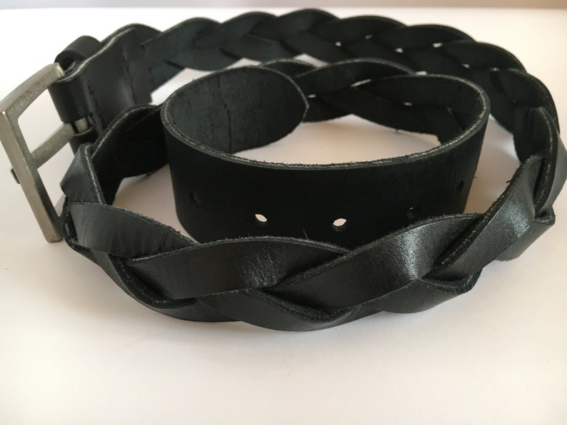 May include: A black leather belt with a braided design and a silver buckle.