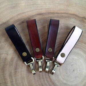 Puede incluir: Cuatro llaveros de cuero con clips giratorios de latón. Los llaveros son de color negro, marrón, burdeos y crema.