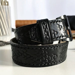 May include: Black leather watch band with a textured pattern and a silver buckle.