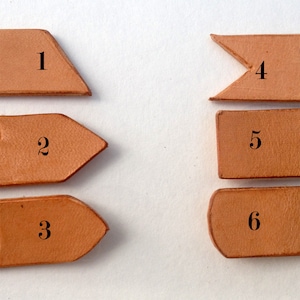 May include: Six different leather pieces with numbers 1 through 6 printed on them. The pieces are all different shapes and sizes.