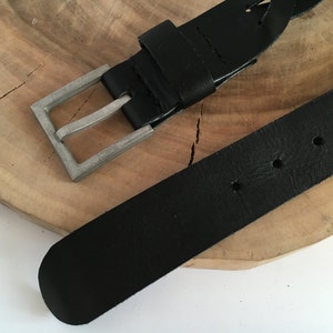 May include: A black leather belt with a braided design and a silver buckle.