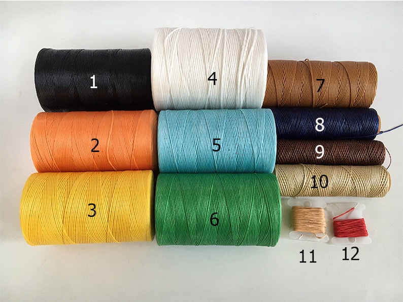May include: Twelve spools of waxed thread in various colors, including black, white, orange, yellow, blue, green, brown, and beige. The spools are numbered 1 through 12.
