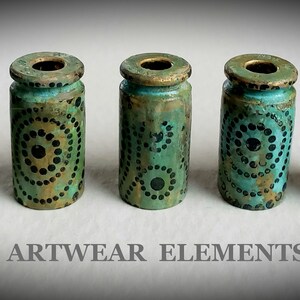 May include: Five teal and gold cylindrical bottle stoppers with black and gold dot patterns. ARTWEAR ELEMENTS.