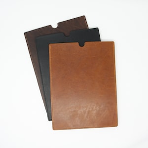 May include: Three leather document folders in brown, black, and tan. The folders are stacked on top of each other.