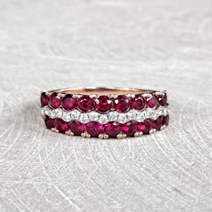 May include: A rose gold band ring with three rows of red ruby stones and a single row of white diamonds.