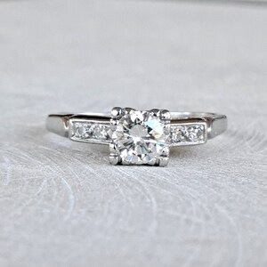 May include: A silver engagement ring with a large, round, clear diamond center stone and smaller diamonds set in a band.