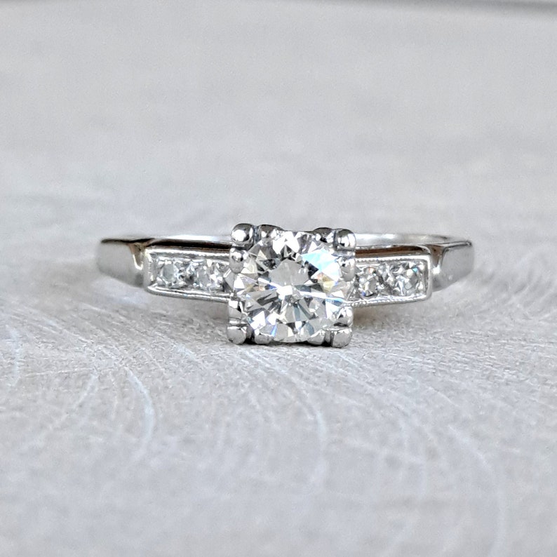 May include: A silver engagement ring with a large, round, clear diamond center stone and smaller diamonds set in a band.