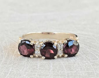 Anillo de tres piedras de oro amarillo de 14 quilates con granate y diamantes.