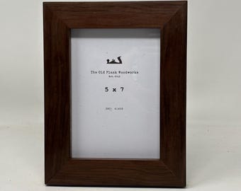 May include: A dark brown wood picture frame with a white mat. The frame is 5 inches by 7 inches and has the text "The Old Plank Woodworks Est. 2013" and "SKU: 41408" printed on the mat.